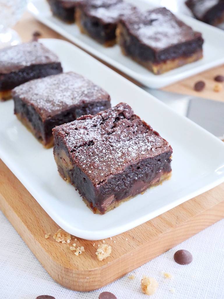 Brownie med brynt smör och mascarponefluff 9 En bit brownie med cookie dough, pudrad med florsocker, på en vit tallrik.