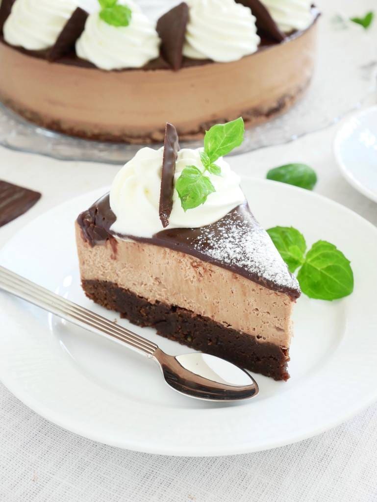 No bake blåbärscheesecake 10 En bit cheesecake med mintchoklad, grädde och chokladdekoration på en tallrik.