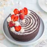 En rund karusellkladdkaka dekorerad med grädde och jordgubbar på toppen.