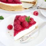 En bit halloncheesecake med färska hallon och bär på en vit tallrik.