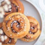 Tre kanelbullar med socker på en grå tallrik.