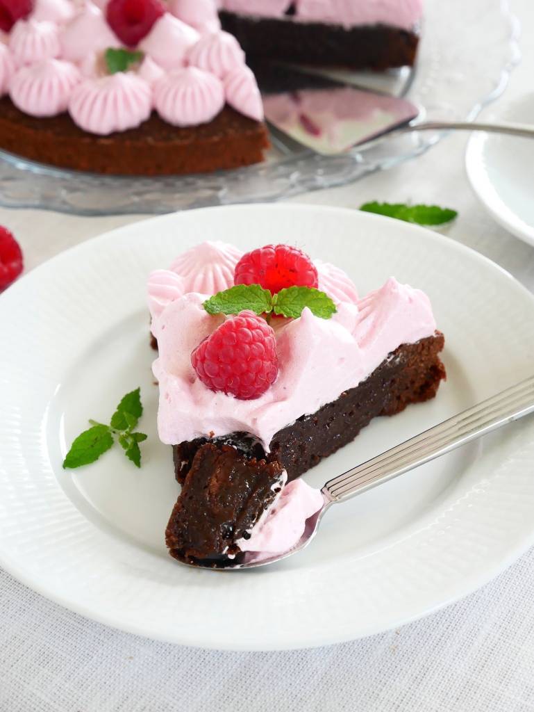 Världens godaste kladdkaksmuffins 9 En bit kladdkaka med hallonmaräng, dekorerad med hallon och mynta på en vit tallrik.