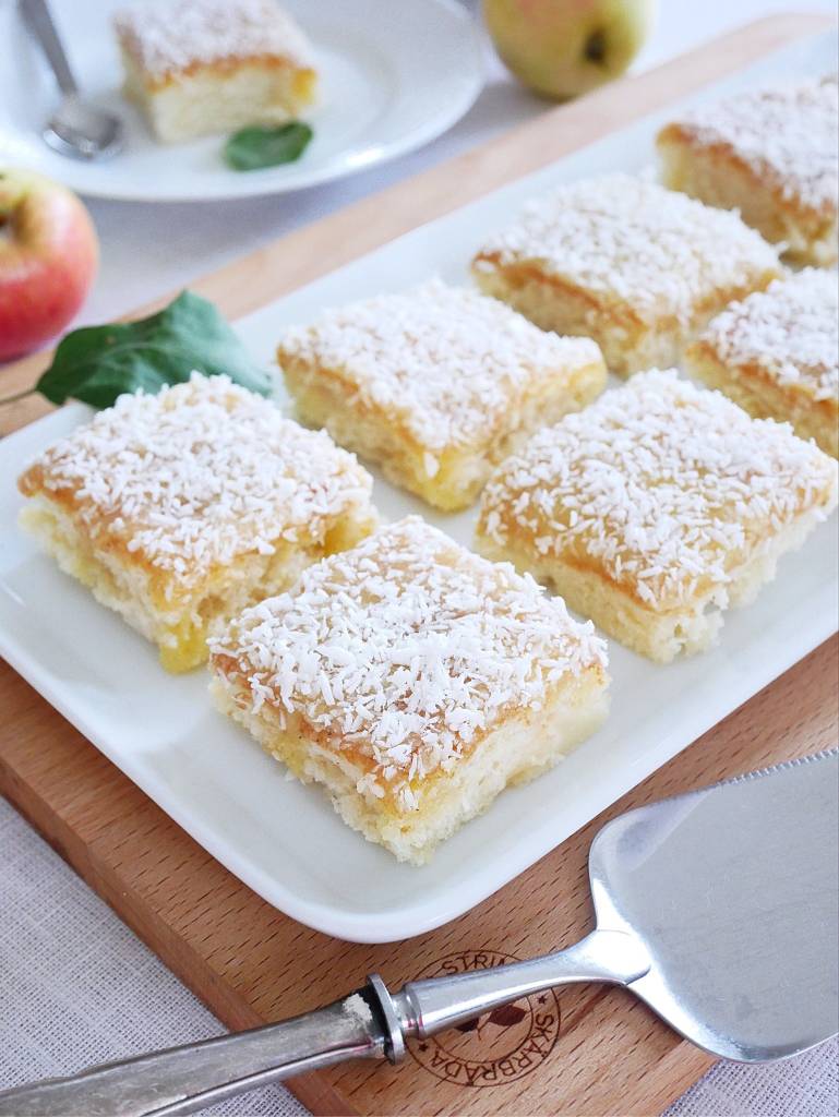 Kärleksmums med extra glasyr 9 En plåt med silviakaka skuren i bitar, toppad med kokosflingor och äppelbitar.