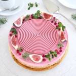 Lingoncheesecake dekorerad med fikon, lingon och gröna kvistar på en tallrik.