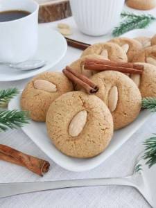 En tallrik med pepparnötter dekorerade med mandlar och kanelstänger.