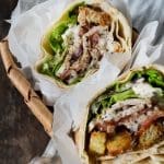Två wraps med kyckling, grönsaker och sås i en korg med papper.