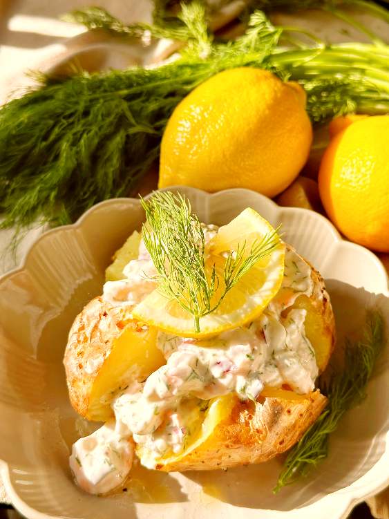 Kycklingröra 11 Bakad potatis toppad med skagenröra och citronskivor på en tallrik.