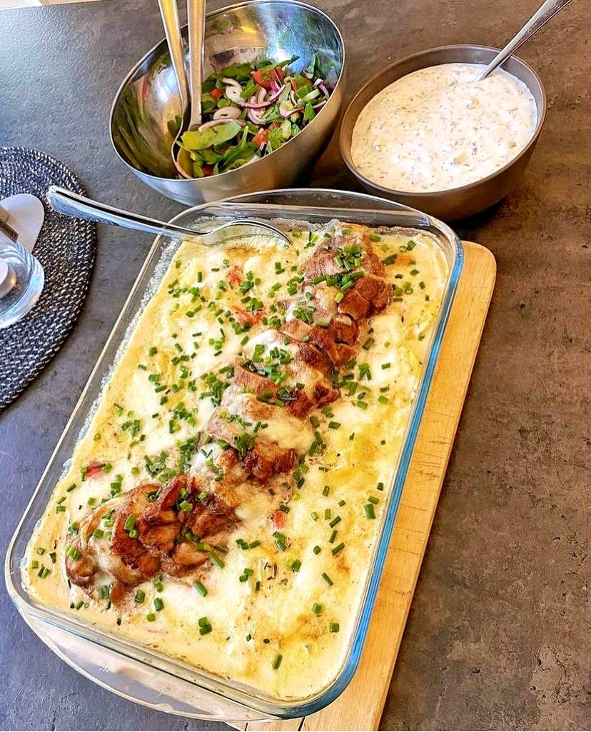 Hasselbacksfläskfilé med soltorkade tomater och fetaost 9 En ugnsform med fläskfilé och potatisgratäng toppad med fetaost, serverad med sallad och sås.