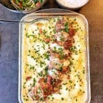 En ugnsform med fläskfilé och potatisgratäng, toppad med gräslök.