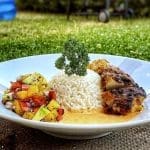 Grillad kycklingfilé serverad med ris och en färgglad salsa på en vit tallrik.