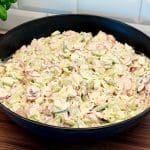 En stor skål med kramig grillsallad som innehåller skivade grönsaker och dressing.