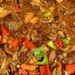 En gryta med långkokt chili som innehåller högrev och olika grönsaker som paprika och morötter.