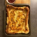 Ugnsbakad flaskpannkaka med bacon i en plåt, serverad med en skål lingonsylt.