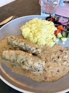 Två oxrullader i gräddsås serverade med ris och en blandad grönsallad.
