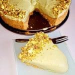 Pistagecheesecake med en bit skuren och serverad på en tallrik med gaffel.