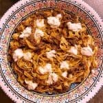 Tallrik med pasta, ragu bolognese och gräddfil i en dekorativ skål.