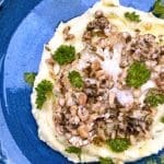 Rostad blomkålsstek placerad på mandelpotatispuré med örter och nötter.
