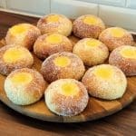 En tallrik med solskensbullar, sockerbelagda med en gul fyllning i mitten.