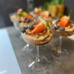 Tiramisu serverad i glas med jordgubbar och blåbär som dekoration.