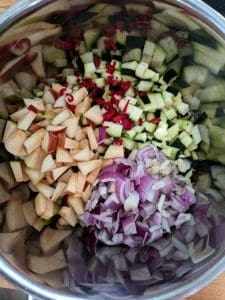 En kastrull med hackade grönsaker inklusive zucchini, äpple, lök och chili.