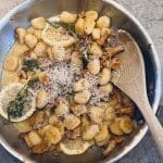 En skål med gnocchi, kantareller, citron och riven ost, serverad med en träsked.