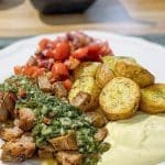 Grillad fläskkarré serverad med ugnsbakade potatisar och sås på en tallrik.