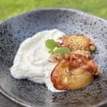 En skål med grillad persika och yoghurt, garnerad med mynta.