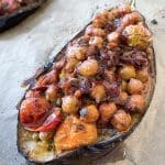 Ugnsbakad aubergine fylld med tomater och andra grönsaker på en plåt.