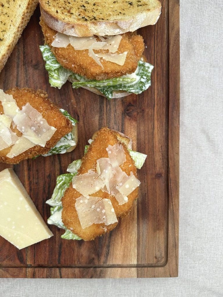Hot tuna melt 6 Tre caesarsalladsmörgåsar med krispig kyckling och parmesan på en skärbräda.