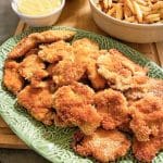 En tallrik med friterade kycklingnuggets i olika former och storlekar, serverade med sås.