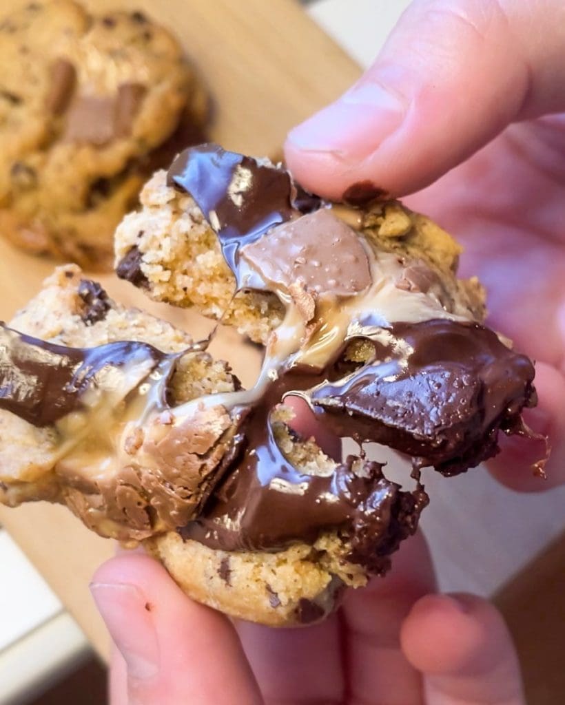 Nutellacookies 9 En person som håller en chokladchip-kaka med smält Dumle i mitten.