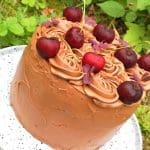 Chokladtårta dekorerad med körsbär och blommor på toppen.