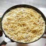 Kramig ost- och skinkpasta i en stor stekpanna med spagetti och sås.