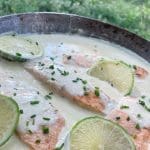 Laxfiléer i en krämig sås med lime och gräslök i en skål.