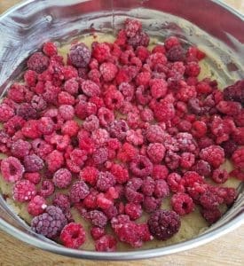 En bakform med en kaka täckt av frysta hallon i olika nyanser av röd.