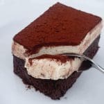 En bit tiramisu brownie med ett lager av krämig fyllning och kakaopulver på toppen.