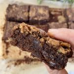En hand som håller en bit brookie med choklad och kakdeg, med en mjuk insida.