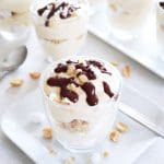 Dulce de leche dessert i ett glas med grädde, chokladsås och nötter på toppen.