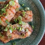 Friterade vietnamesiska vårrullar med tofu, toppade med grön lök och sesamfrön på en grön tallrik.