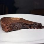 En bit fudge brownie med smält chokladcenter på en vit tallrik.