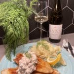 Två friterade fiskfiléer med potatismos och en sås, dekorerade med dill och citron.