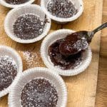 Sju kladdkaksmuffins i pappersformar, med ett lager av florsocker på toppen.