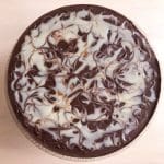 En rund kladdkaka med en mönstrad glasyr av choklad och vit choklad.
