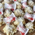 En träskiva med Raffaello-kakor och inpackade Raffaello-godis.