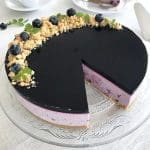Blåbärscheesecake med svart glasyr och blåbär på toppen, skuren i en bit.