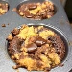 Chokladchip kladdkaksmuffins i en muffinsplåt med chokladbitar på toppen.
