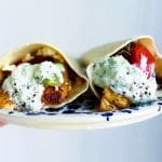 Två grekiska halloumiwraps med grönsaker och sås på en tallrik.