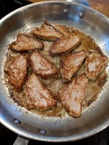 Fläskytterfiléer som steks i en metallpanna med gyllenbrun yta.