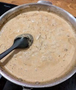 En kastrull med lökgratinerad fläskytterfilé i en krämig sås.