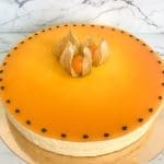Moussetårta med en slät orange yta och dekorationer av physalis och svarta prickar.